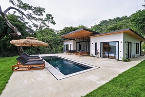 A modern house with a swimming pool, lounge chairs, and a covered patio area. - Villa Alba (Cóbano)