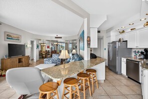 Een moderne keuken met een granieten aanrecht, roestvrijstalen apparatuur en een bar met krukken.