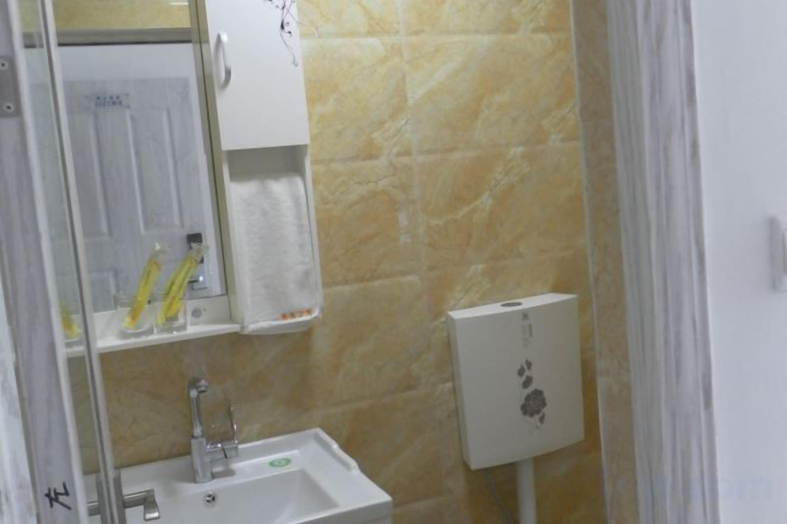 Un baño con lavamanos, espejo y dispensador de toallas.