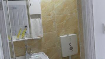 Un baño con lavamanos, espejo y dispensador de toallas.