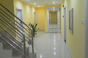 A corridor with a staircase on the left, a potted plant, and doors leading to other areas. - Meimei Apartment (Nanchang County)
