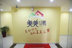 A reception area with a logo, a potted plant, and a red carpet. - Meimei Apartment (Nanchang County)