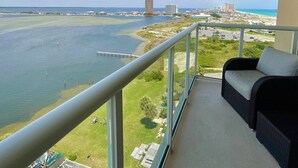 Un balcón con vista a un puerto deportivo, un puente y edificios lejanos.