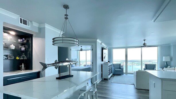 Una cocina moderna con una isla central, taburetes de bar y una lámpara colgante.