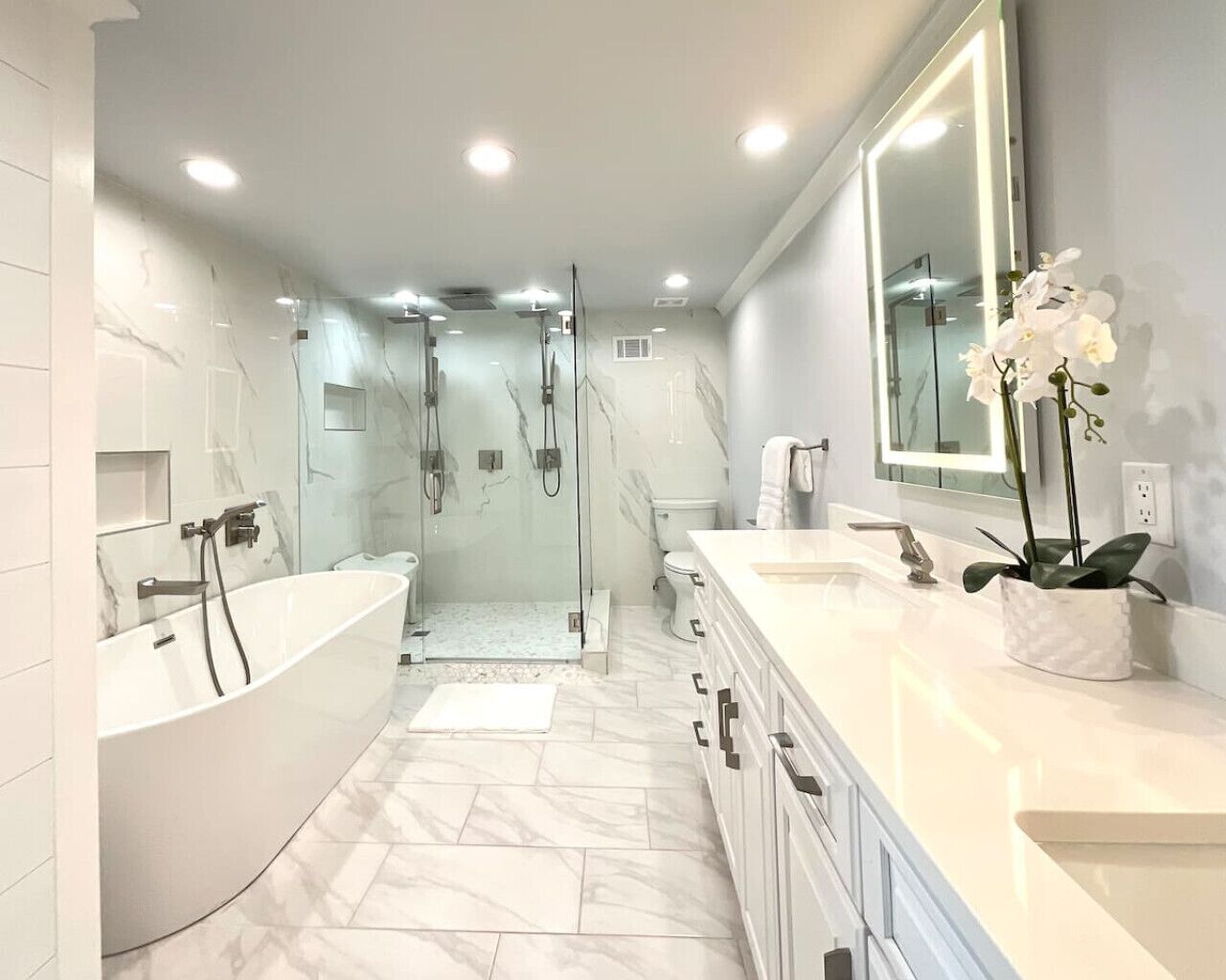A modern bathroom with a freestanding bathtub, a glass-enclosed shower, and a vanity with a large mirror.