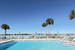 Ein Swimmingpool mit Liegestühlen und Palmen, umgeben von einem weißen Zaun.
