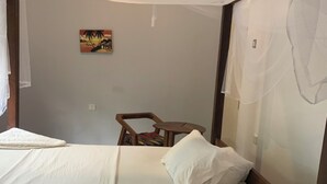 A single bed with white bedding, a ceiling fan, and a small table with a chair.