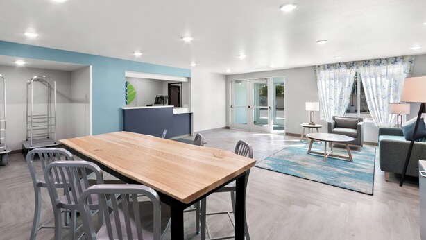 Un amplio salón con una mesa de comedor de madera, sillas grises, un sofá y una mesa de centro.
