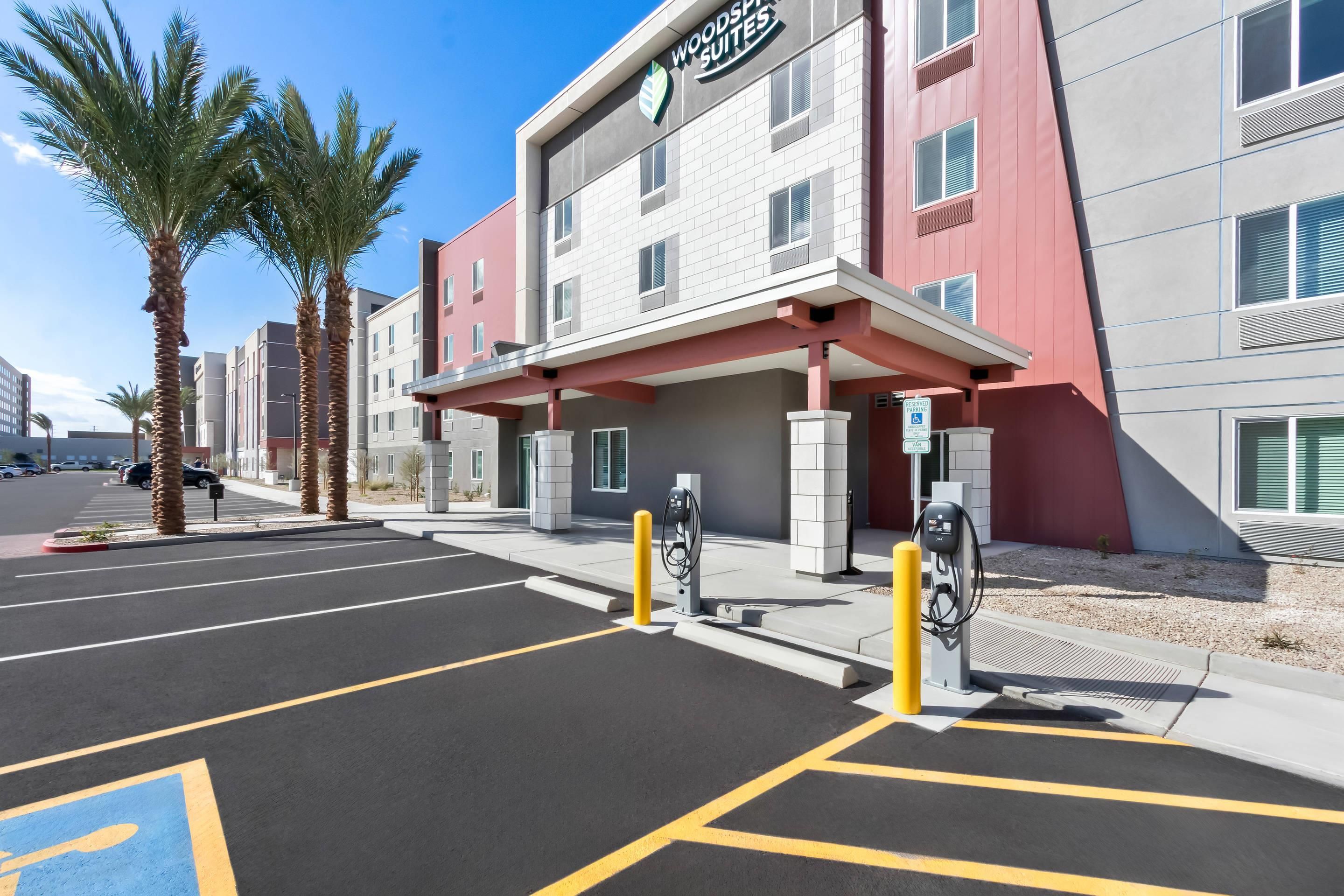 Un hôtel doté d’une façade moderne, d’un parking avec des places délimitées et de bornes de recharge pour véhicules électriques.