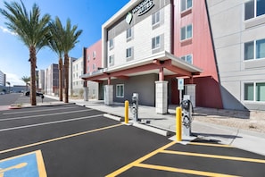 A hotel with a modern facade, a parking lot with marked spaces, and electric vehicle charging stations. - WoodSpring Suites Chandler Phoenix Medical Center (Chandler)