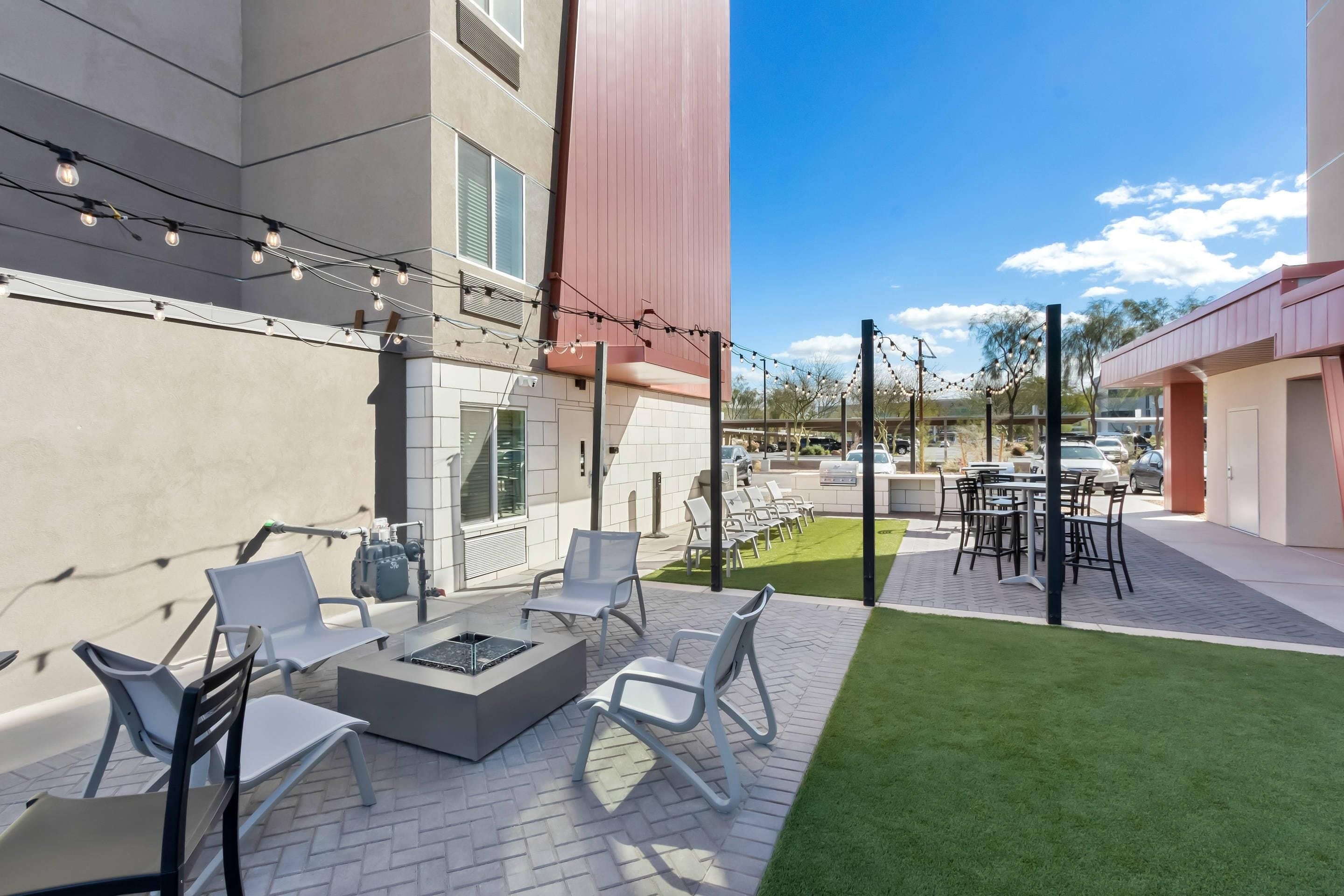 Un patio exterior con mobiliario, una chimenea y luces colgantes.