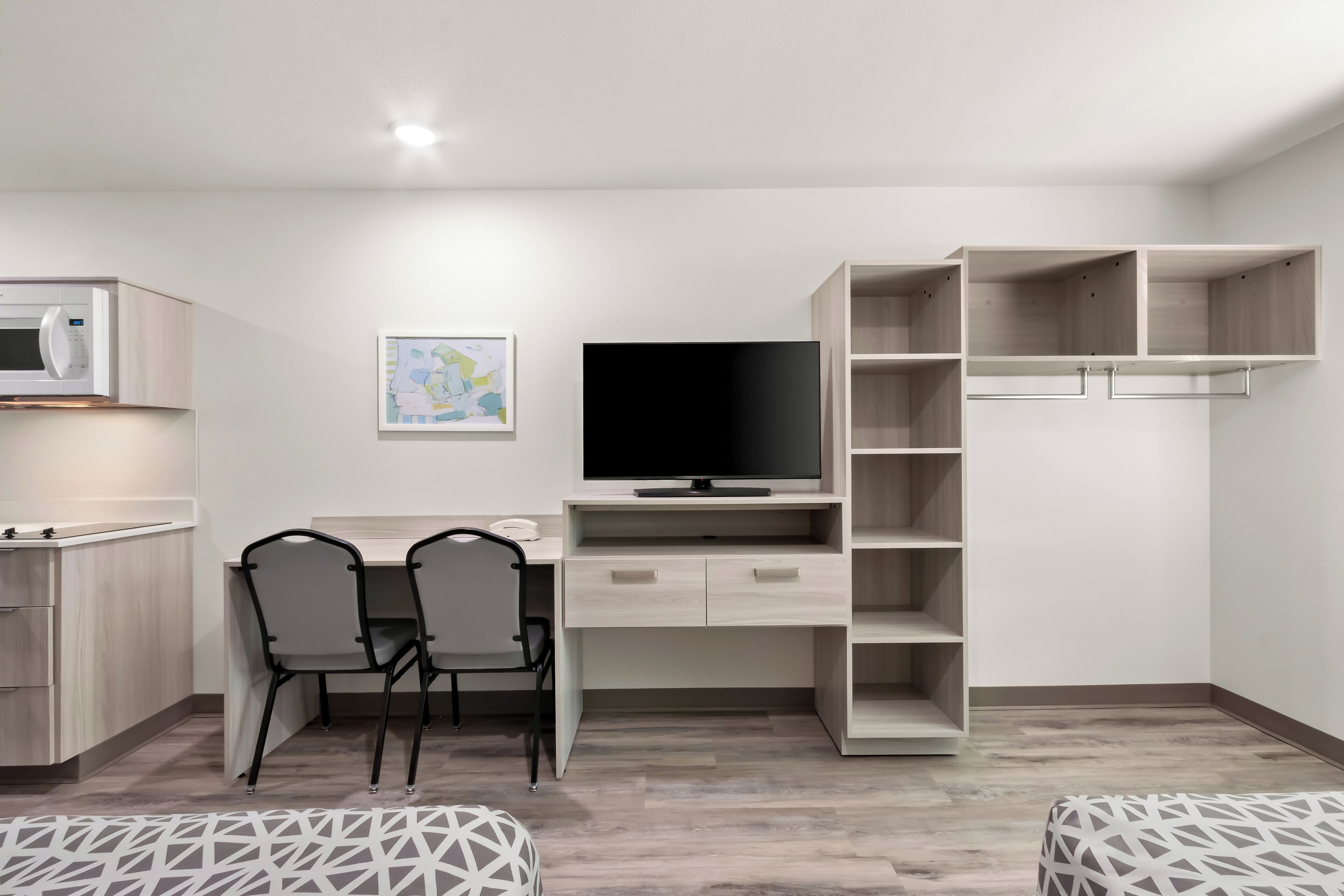 Een moderne slaapkamer met een bed, een bureau met stoel, een televisie en een kledingkast.