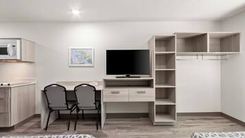 Een moderne slaapkamer met een bed, een bureau met stoel, een televisie en een kledingkast.