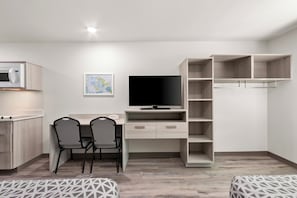Un dormitorio moderno con cama, escritorio con silla, televisor y armario.