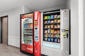 A vending machine with a Coca-Cola branded section and a variety of snack options. - WoodSpring Suites Chandler Phoenix Medical Center (Chandler)