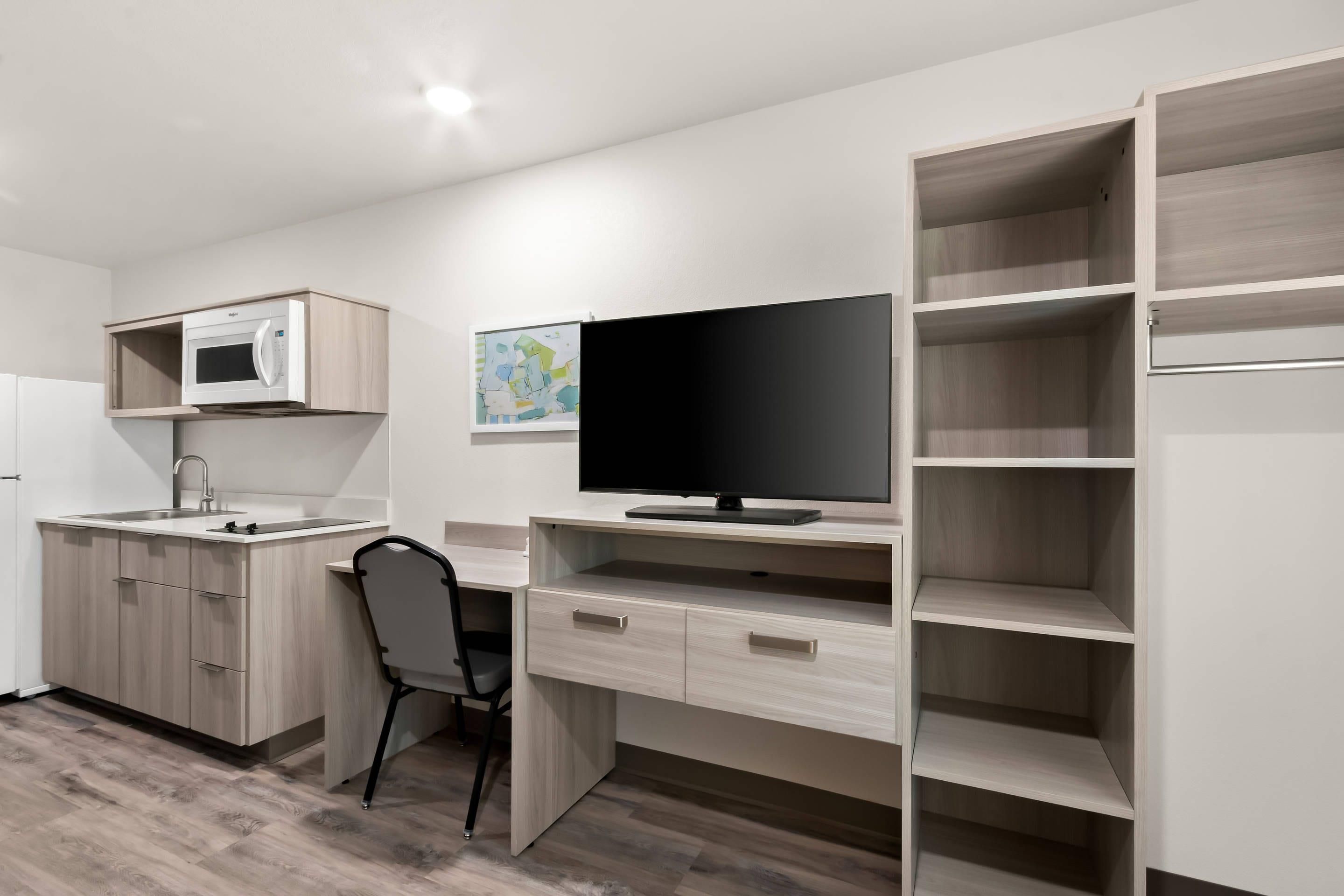 A compact kitchenette with a microwave, sink, and cabinet.