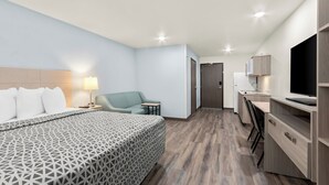 Una habitación de hotel moderna con una cama grande, un escritorio, una silla y un televisor.
