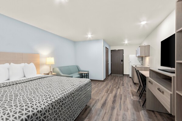A modern hotel room with a large bed, a desk, a chair, and a TV. - WoodSpring Suites Chandler Phoenix Medical Center (Chandler)