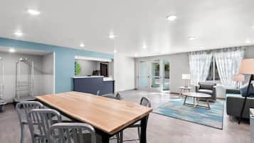 Una sala de estar moderna con una mesa de comedor de madera, sillas grises, un sofá gris y una alfombra azul.