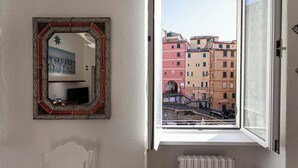 A room with a large window, a mirror with a decorative frame, and a radiator below the window. - La casa di Nanni a Camogli by Wonderful Italy (Camogli)