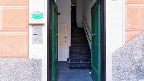A staircase leading to a door with a green frame, a wall-mounted sign, and a number '5' plaque. - La casa di Nanni a Camogli by Wonderful Italy (Camogli)
