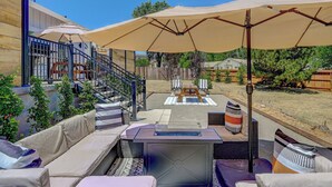 Un espace patio aménagé avec du mobilier d’extérieur, un barbecue et de grands parasols pour créer de l’ombre.