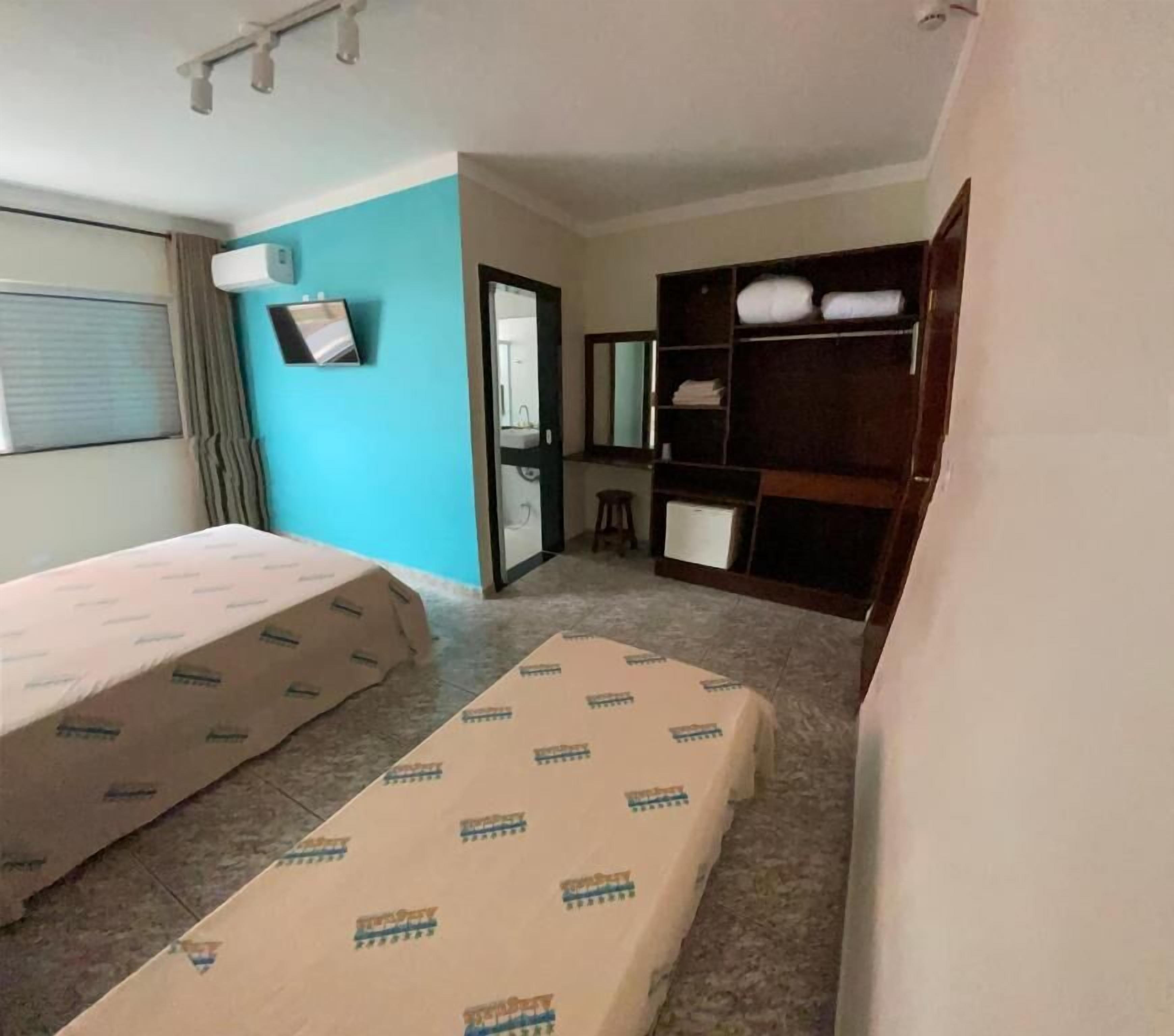 Una habitación de hotel pequeña con dos camas, un escritorio, un espejo y un armario.