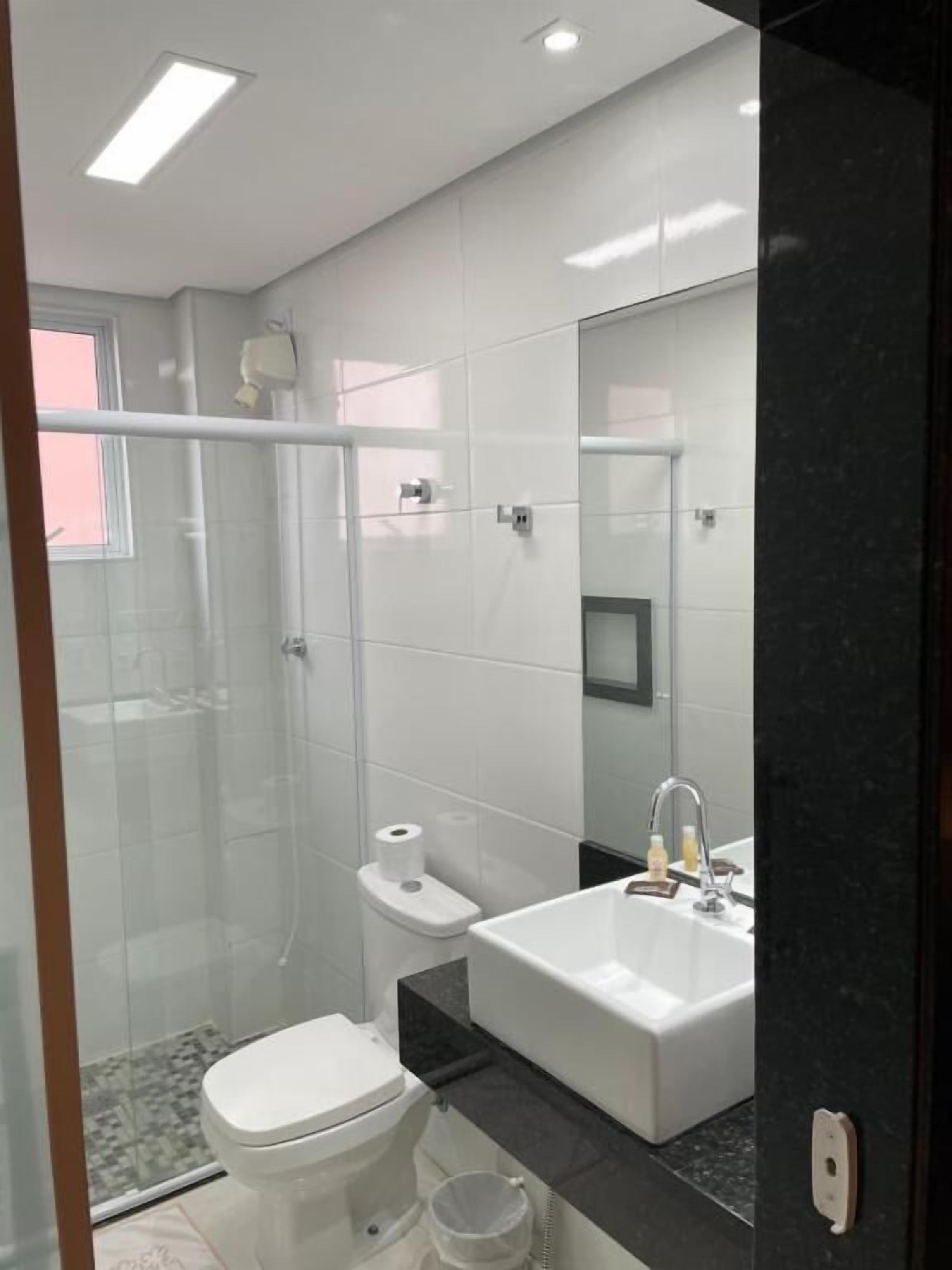 Een moderne badkamer met een douchecabine van glas, een toilet en een wastafel met spiegel.