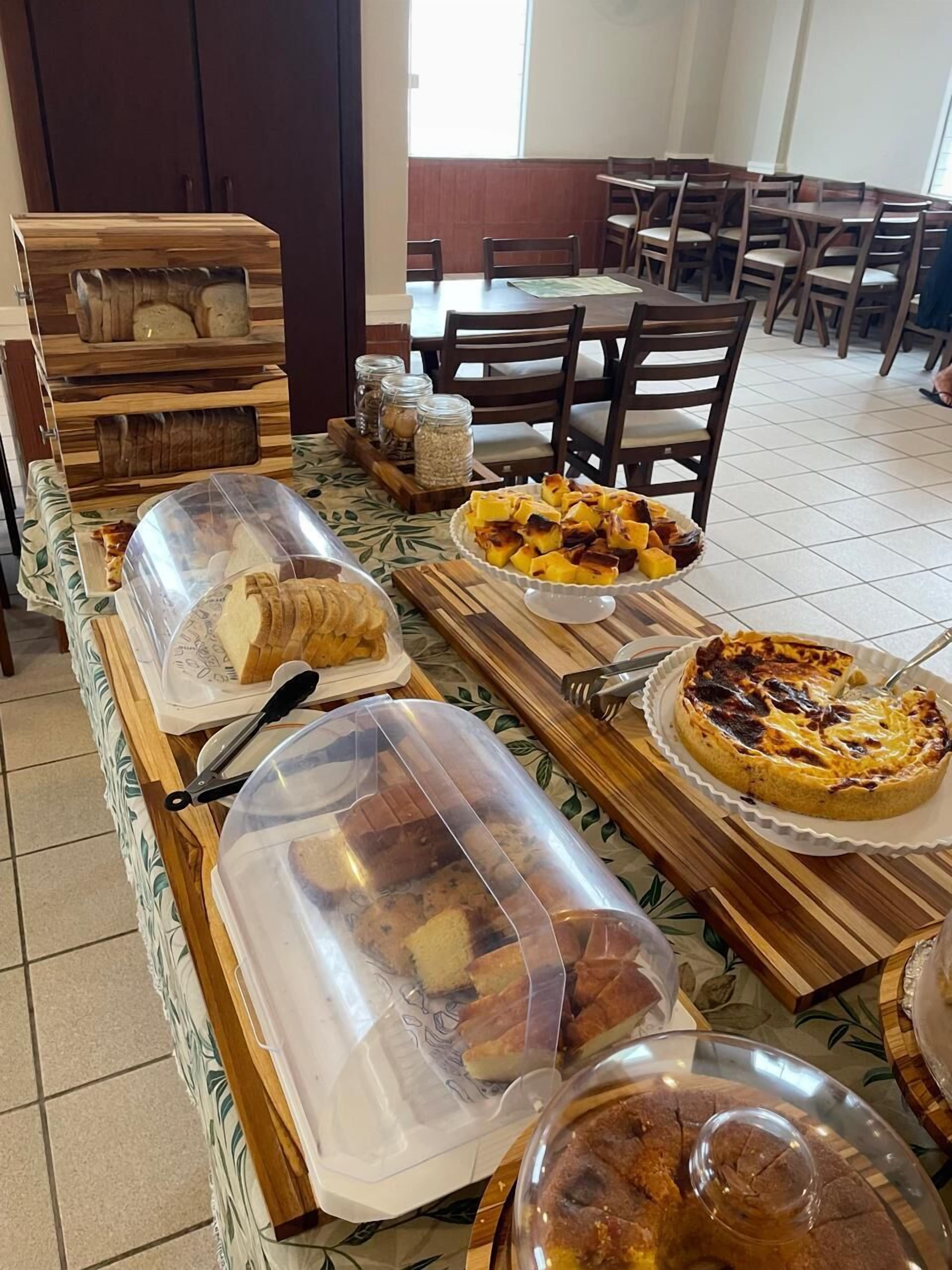 A buffet setup with various food items, including a quiche, a fruit platter, and bread.