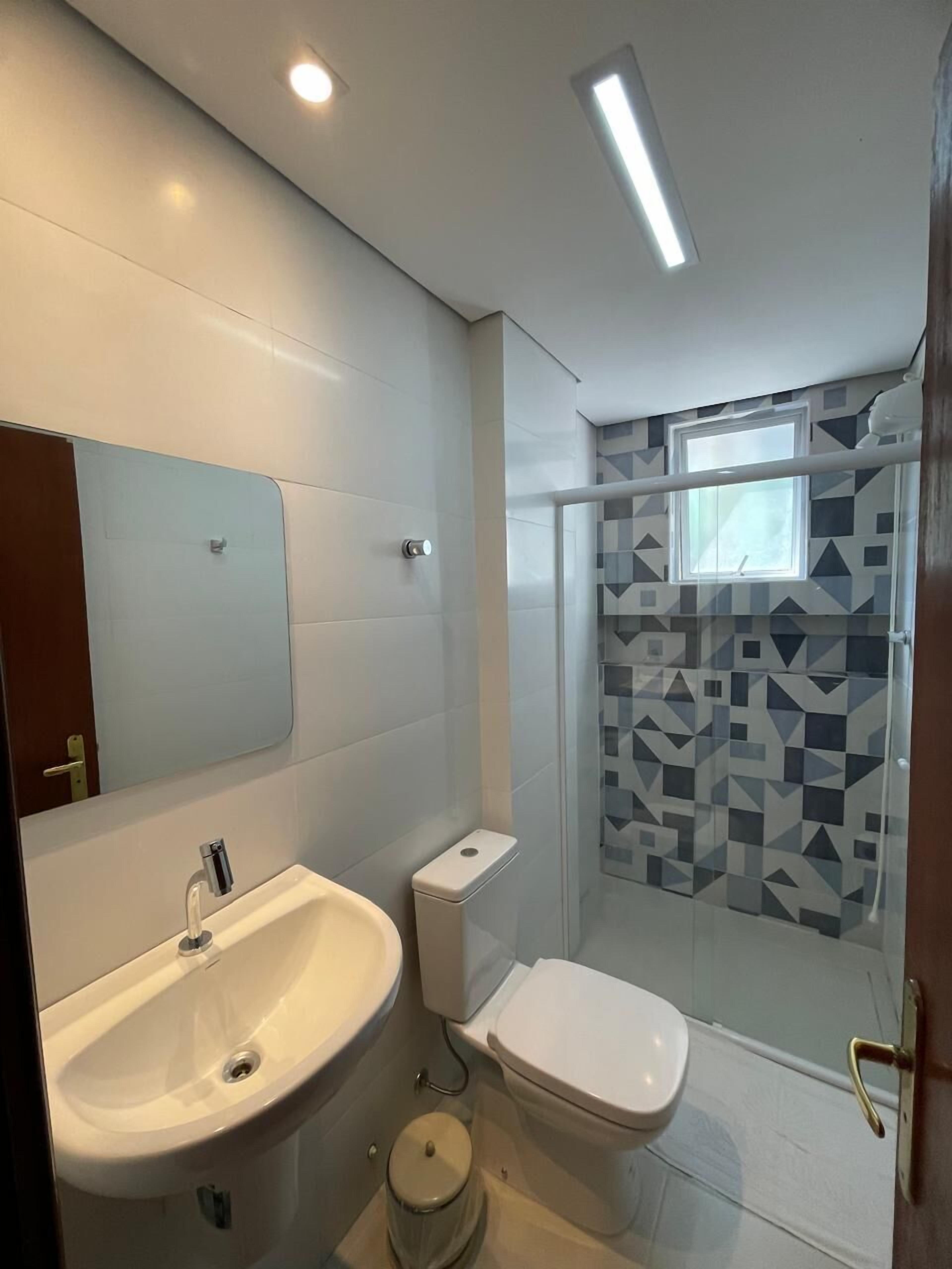 A modern bathroom with a sink, toilet, and shower.