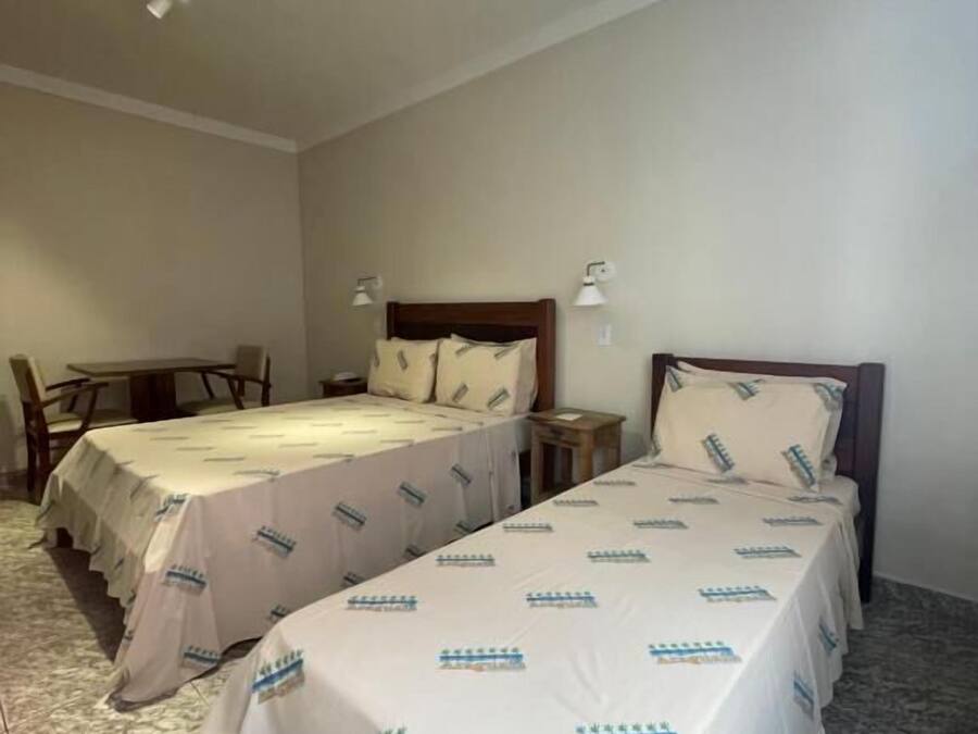 Habitación de hotel con dos camas, una mesita y una mesita de noche.