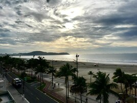 A beach with palm trees, a road, and a distant view of the ocean.