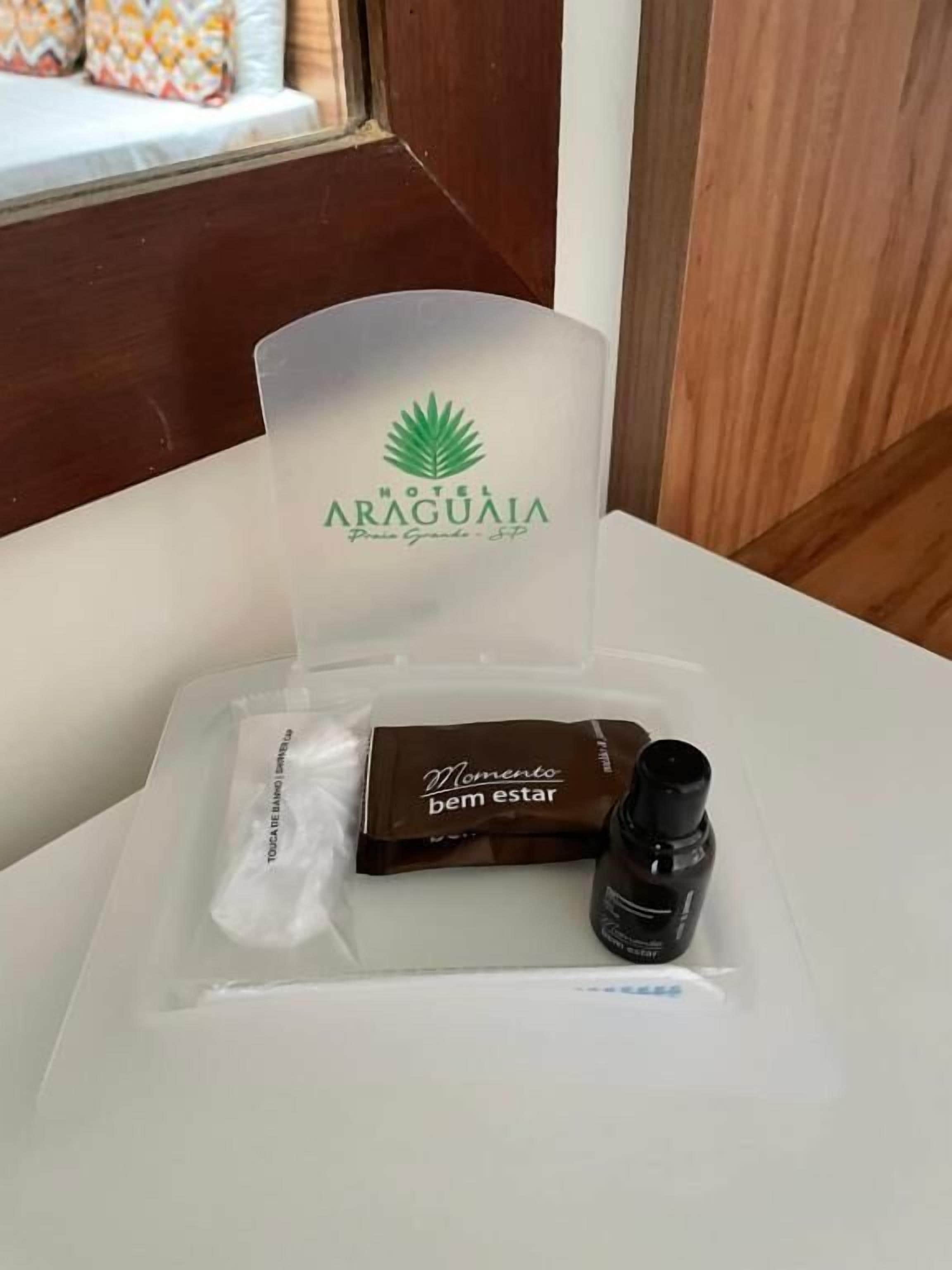 Habitación de hotel con una mesa blanca que muestra una botella de loción, una pastilla de jabón y un frasco pequeño de champú.