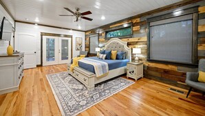 Un dormitorio con cama, ventilador de techo, ventana, mesita de noche, silla y cómoda.