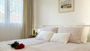 Una cama doble con ropa blanca de cama y un ramo de rosas rojas.