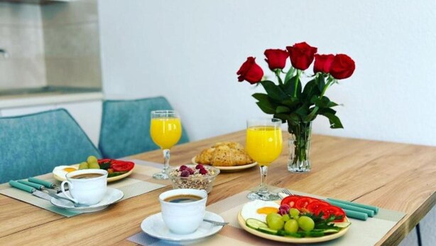 Una mesa de desayuno con café, jugo de naranja, croissants y una bandeja de fruta.