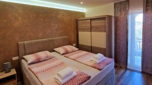 Un dormitorio con cama, mesitas de noche, armario y puerta corrediza de cristal a un balcón.