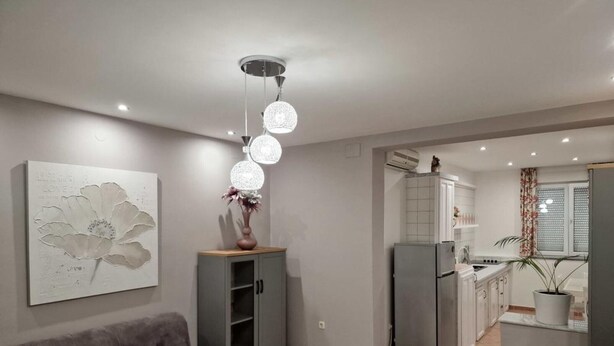 A modern living room with a grey sofa, a decorative wall piece, and a unique spherical light fixture. - Pansion Belvedere - One Bedroom (Magnolia) (Mali Losinj)