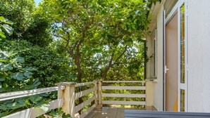 A covered outdoor area with a wooden bench, a white railing, and a door leading to a building. - Pansion Belvedere - One Bedroom (Magnolia) (Mali Losinj)
