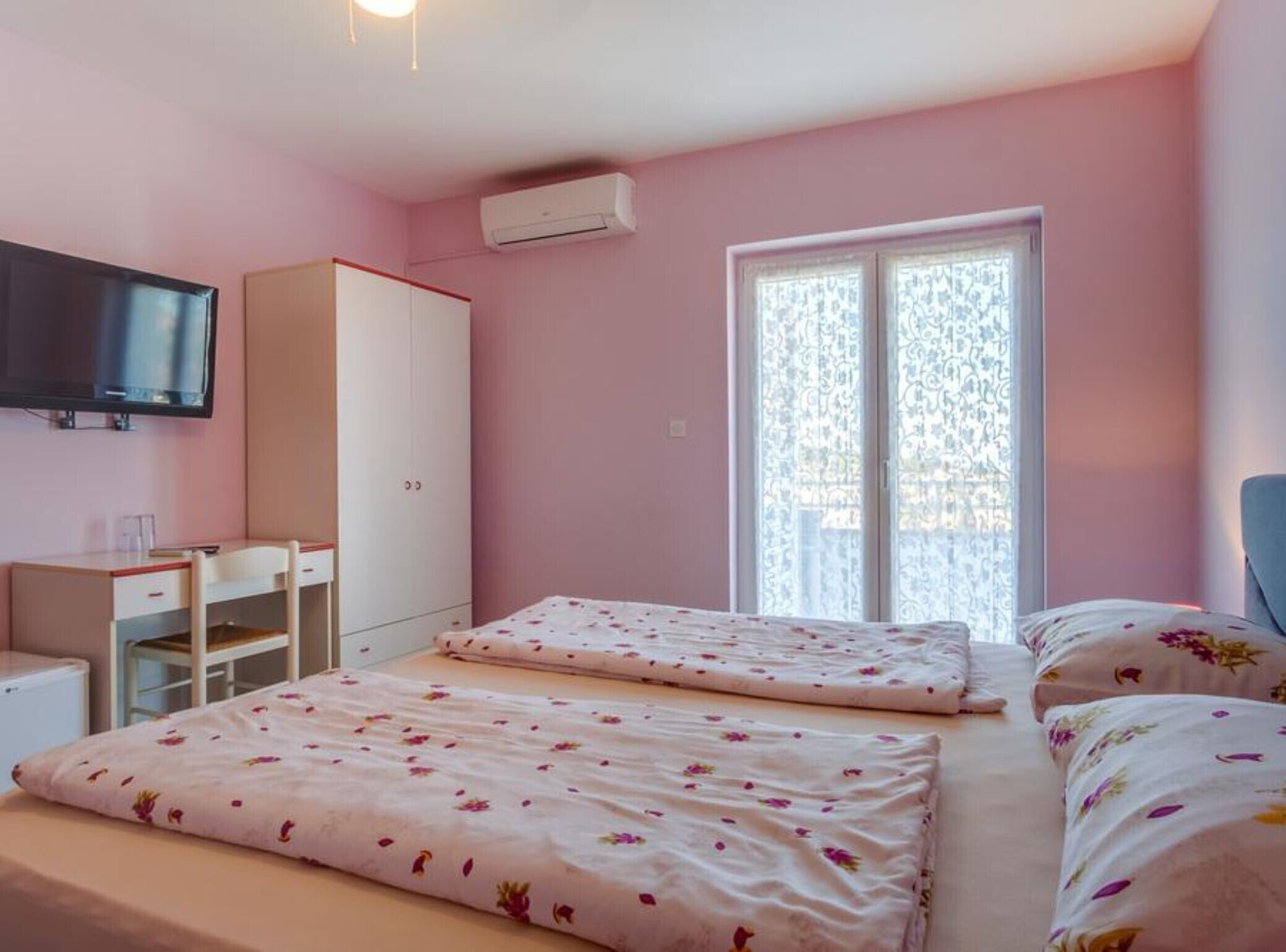 Une chambre avec deux lits, un bureau, une armoire et un téléviseur.