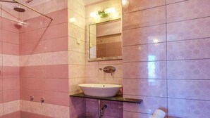 A bathroom with pink tiles, a white sink, a mirror, and a towel on a small table.