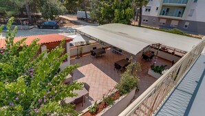 Eine Dachterrasse mit Außenbestuhlung, umgeben von Bäumen und einem geparkten Auto.