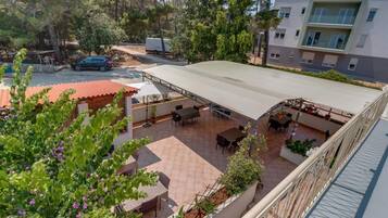 A rooftop patio with outdoor seating, surrounded by trees and a parked car.