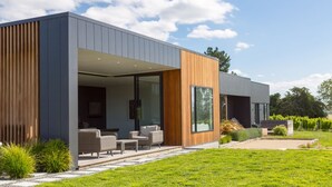 A modern house with a large open patio, outdoor seating, and a well-maintained garden. - 89 In The Vines, Martinborough (Martinborough)