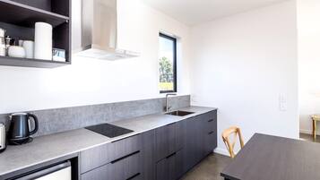 Una cocina moderna con estufa integrada, un lavamanos y un ventanal que proporciona luz natural.