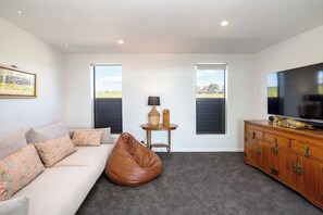 A modern living room with a sofa, a bean bag, a television, and a cabinet.