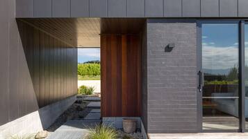 A modern building with a dark facade, a wooden door, and a glass entrance.