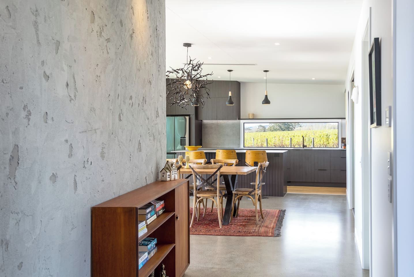 Una cocina moderna con comedor, una estantería y vistas al viñedo.