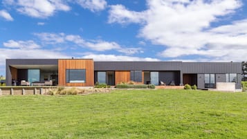 Un bâtiment moderne à deux étages, doté d’un toit plat, de grandes fenêtres et d’une pelouse verdoyante à l’avant.