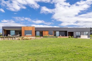 A modern two-story building with a flat roof, large windows, and a grassy lawn in front. - 89 In The Vines, Martinborough (Martinborough)